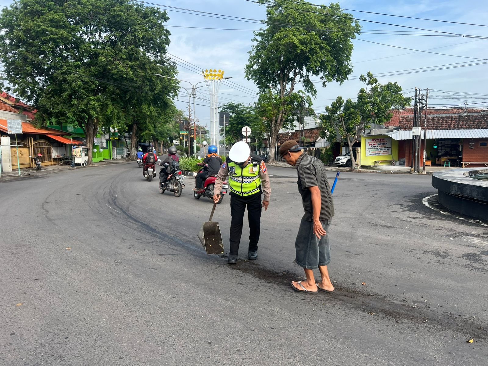Sigap Cegah Kecelakaan, Polantas Nganjuk Bersama Warga Bersihkan Tumpahan Minyak di Bundaran Adipura